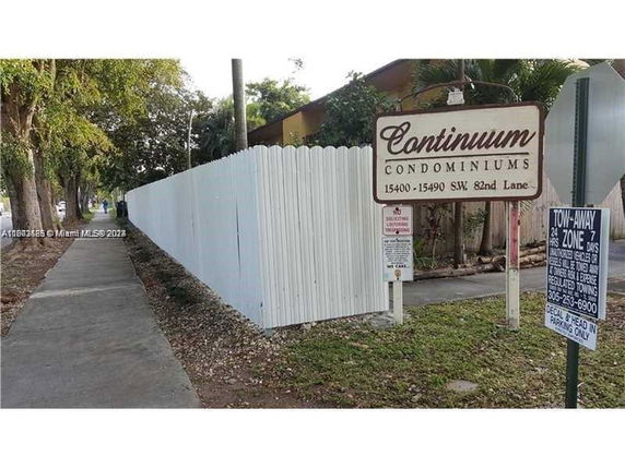 Side view of Continuum Condominiums with a white fence and signage.