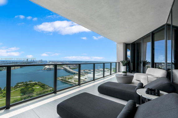 Outdoor balcony with seating area and a panoramic view of the waterfront and cityscape.
