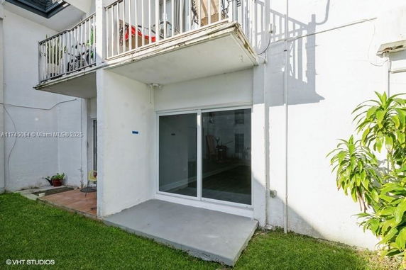 Rear view of a multi-story building with a balcony and sliding glass door.
