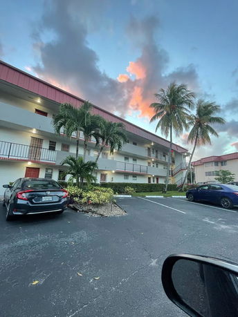 Front view of a multi-story apartment building with parking area.
