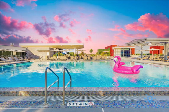 Rooftop area with a swimming pool, lounge chairs, and a pink flamingo float in the water.