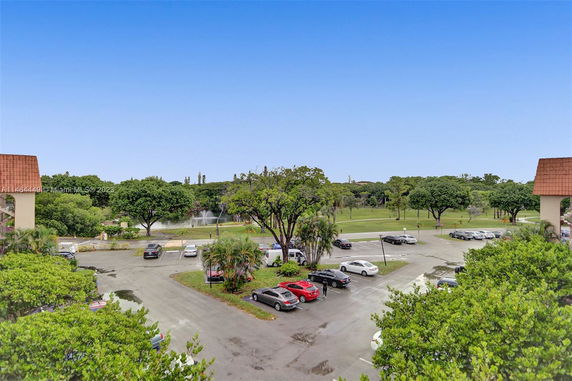 Outdoor parking area with several parked cars and surrounding greenery.