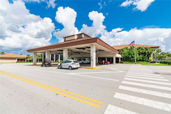 Outdoor parking area with a large canopy structure and several parked vehicles.