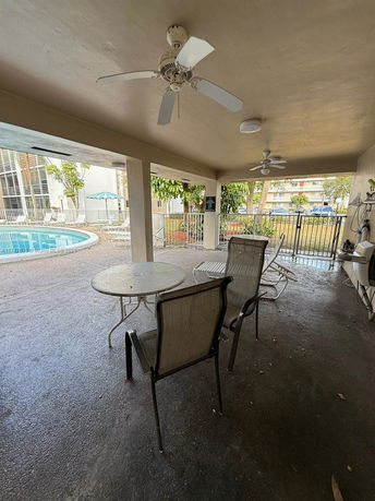 Outdoor area with a swimming pool and seating under a covered patio.