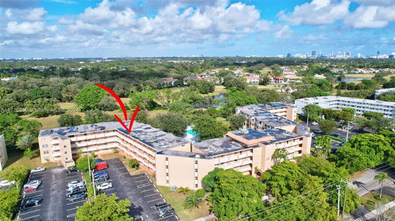 Aerial view of a residential complex with surrounding landscape and distant city skyline.