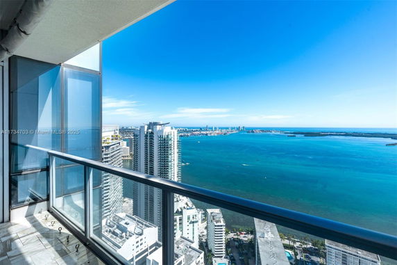 Panoramic view from a high-rise balcony overlooking a cityscape and ocean.