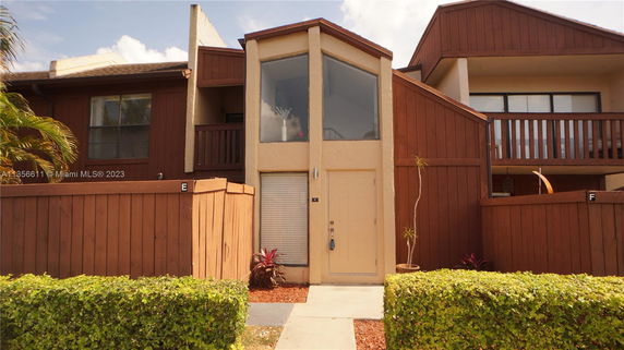 Front view of a multi-story house with wooden paneling and large windows.