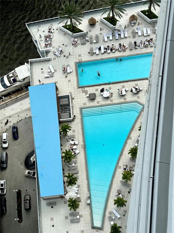 View of a rooftop pool area with loungers and umbrellas.