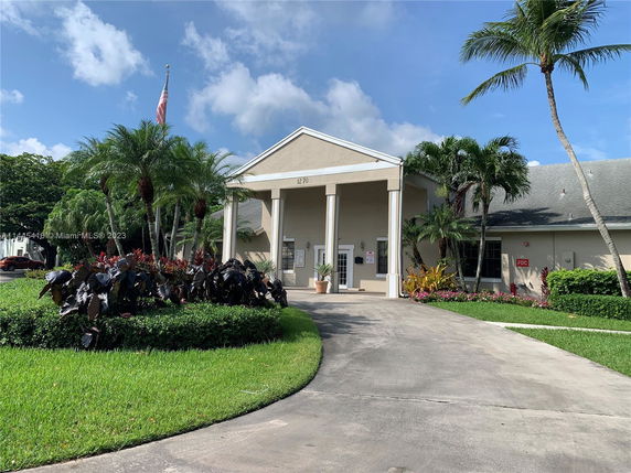 Front view of a building with columns and a manicured entrance.