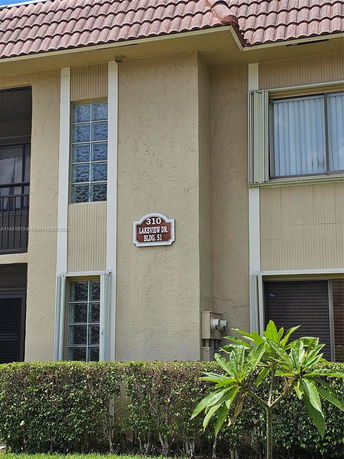 Front view of a residential building with a tiled roof and a sign displaying address.