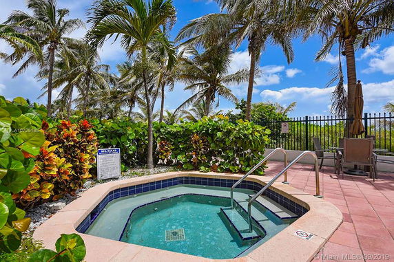 Outdoor view of a small spa pool surrounded by palm trees and greenery.