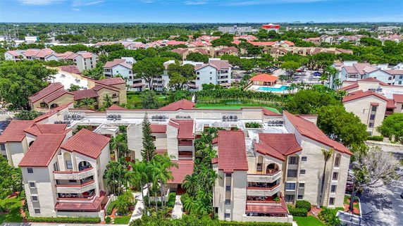 Aerial view of a residential complex with red-tiled roofs and surrounding greenery.