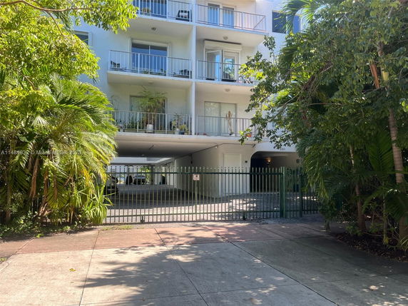 Front view of a multi-story residential building with balconies and gated entrance.