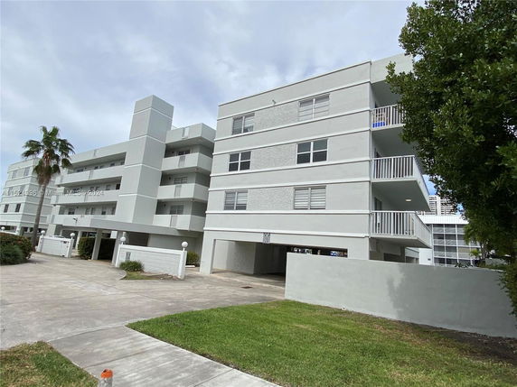 Front view of a multi-story residential building with balconies and a driveway.