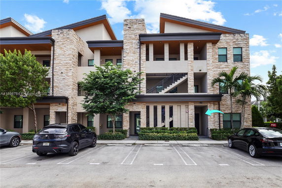 Front view of a multi-story building with stone accents and parking area.