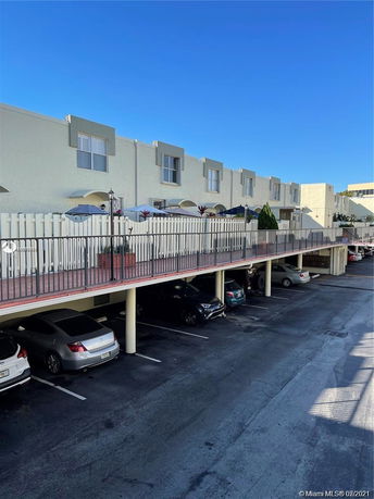 Covered parking area beneath a row of apartment units.