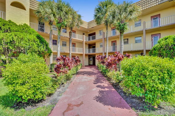 Front view of a multi-story building with balconies and a landscaped entrance.