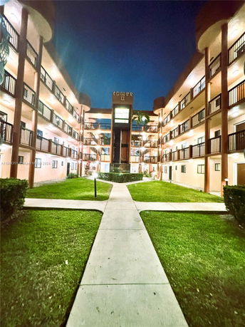 Front view of a multi-story apartment complex with balconies and central path.