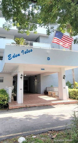 Front view of a multi-story building named Eden Isles with a covered entrance and an American flag.