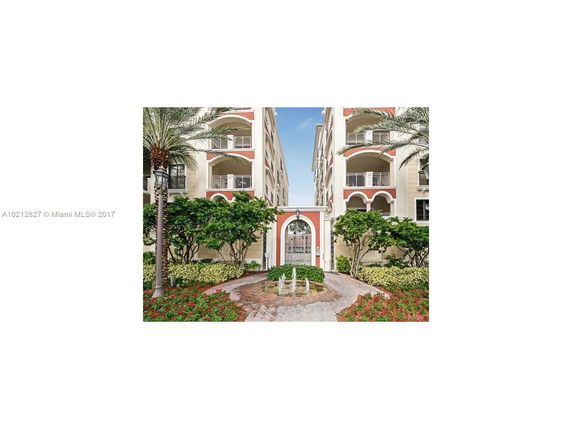 Front view of a multi-story building with arched balconies and landscaped entrance.