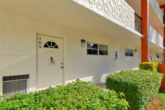 Front view of a building with a white exterior and a doorway numbered 109.