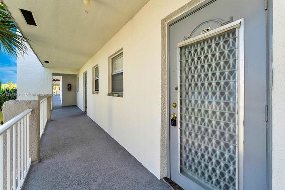 Exterior view of a corridor leading to an apartment unit with a gray door marked 306.