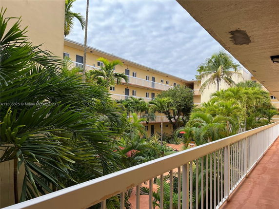 View of apartment complex with exterior corridors and palm trees.