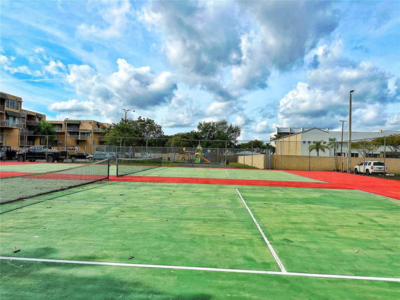 Tennis court with residential buildings in the background.