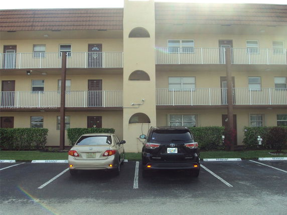 Front view of a multi-story residential building with a parking area in front.