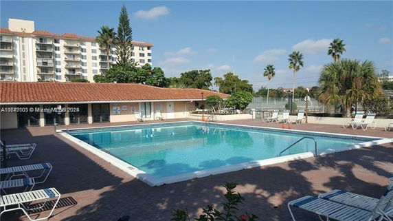 Outdoor swimming pool area with lounge chairs and adjacent building.