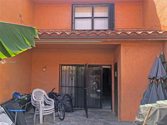 View of a two-story house with an outdoor area, featuring a window and an entrance door with a metal grill.