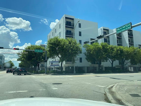 Front view of a multi-story residential building at the corner of a street intersection.