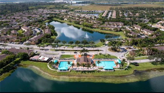 Aerial view of a residential area with a central lake, surrounded by housing and a swimming pool facility.