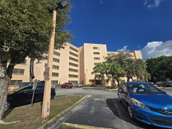 Front view of a multi-story building with a parking area in front.