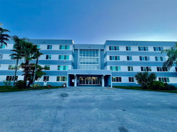 Front view of a four-story building with blue and white exterior and multiple windows.