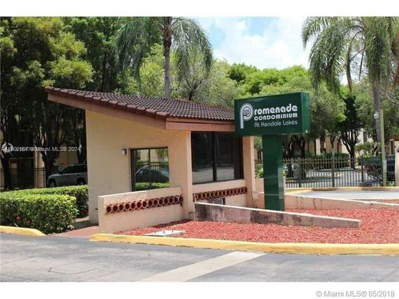 Front view of a small building with a pitched roof and a sign for Promenade Condominium.