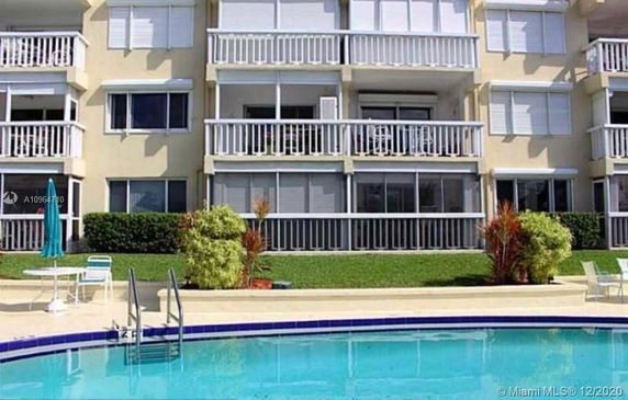 Front view of a multi-story residential building with balconies and pool area.