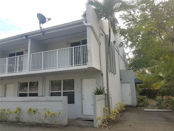 Front view of a two-story residential building with a balcony and satellite dish.