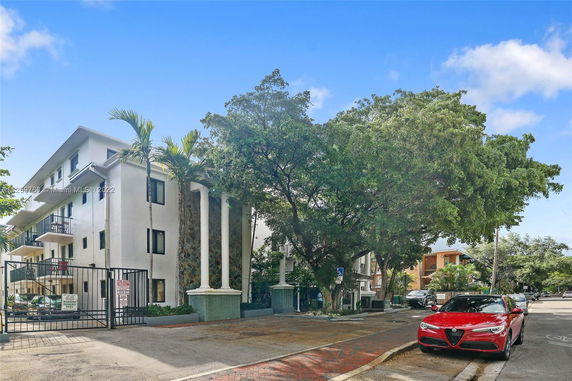 Front view of a multi-story building with balconies and a gated entrance.