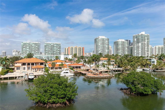 View of a waterfront area with houses and high-rise buildings, seen across a body of water.