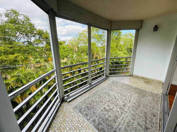 View of surrounding greenery from a balcony with tiled floor.