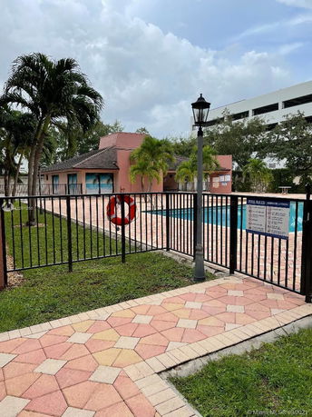 View of a fenced swimming pool area adjacent to a single-story building with a tiled roof.