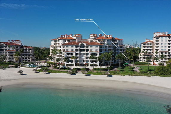 Beachfront view of a large condominium complex with multiple balconies and red-tiled roofs.