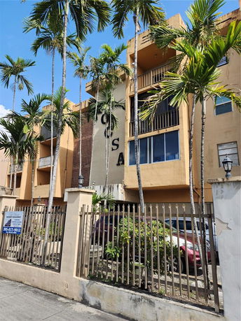 Front view of a multi-story residential building surrounded by palm trees.
