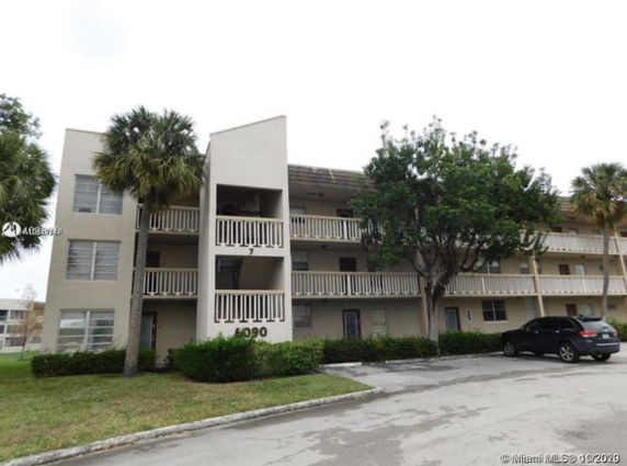 Front view of a multi-story residential building with balconies and parking area.