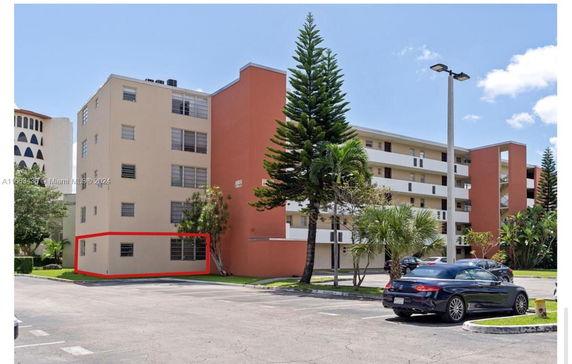 Front view of a multi-story residential building with a parking area.