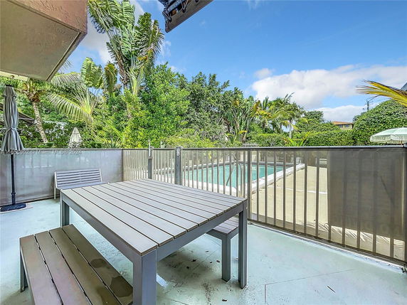Outdoor area with a fenced swimming pool and patio seating.