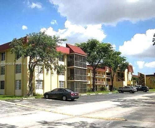 Front view of a multi-story apartment building with a sloped roof and balconies.