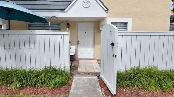 Front view of a small house with a white wooden gate and a covered entrance.