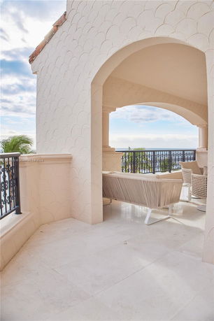 Arched balcony view with wrought iron railings and outdoor seating.